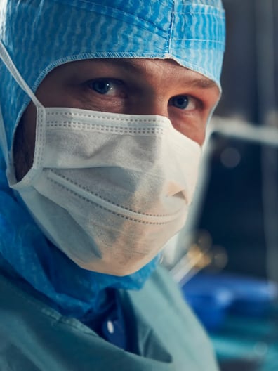 En kirurg med kirurgmask och operationskläder.