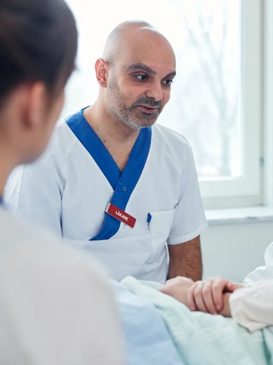 En läkare pratar med en patient i en sjukhussäng.