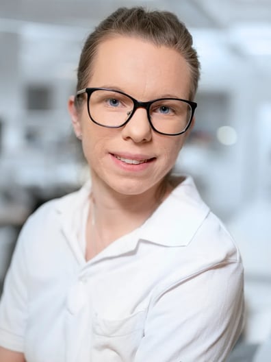 A woman wearing glasses and a white shirt.