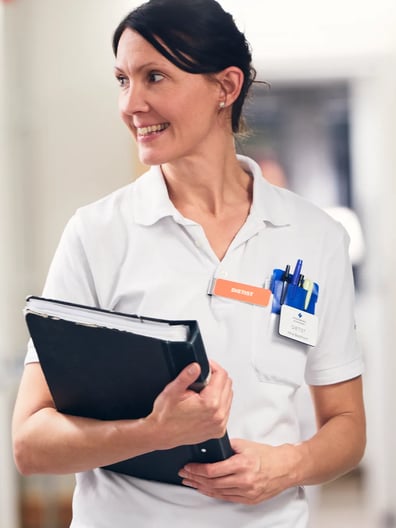 En kvinna i vit skjorta håller i en pärm.