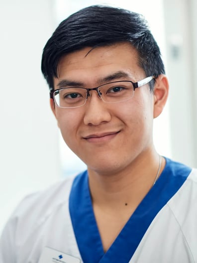 En man i vårdkläder ler mot kameran.