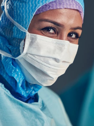 En kvinna iförd kirurgmask och operationskläder.