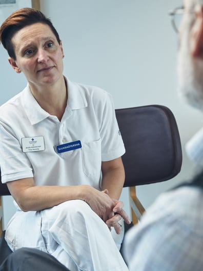 En kvinna sitter i en stol och pratar med en man.