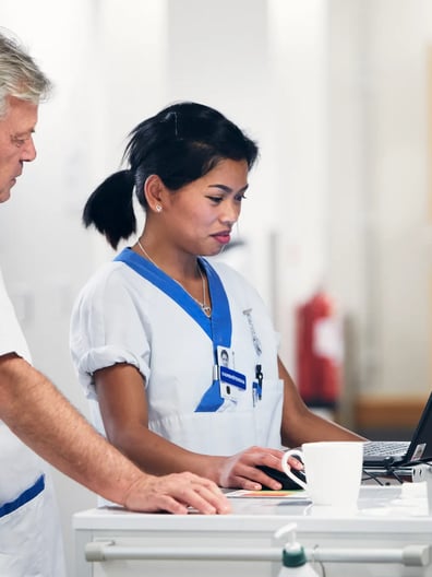 En man och en kvinna står framför en bärbar dator.