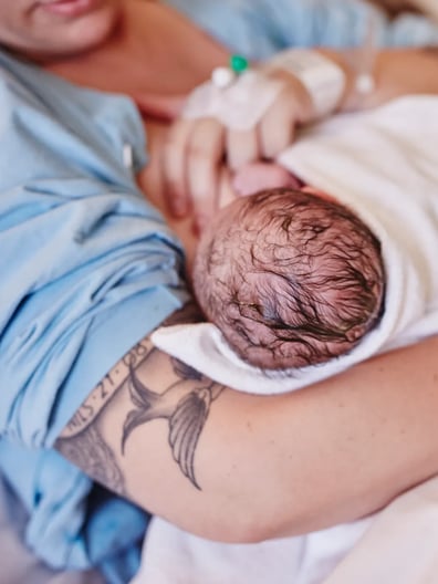 En kvinna håller en baby insvept i en filt.