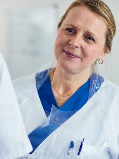 En läkare tittar mot kameran och ler.