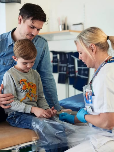 En pappa följer med sin son som undersöks av en läkare.