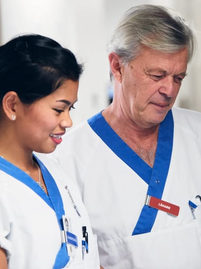 En man och en kvinna i vårdkläder tittar på en surfplatta.