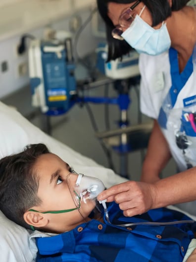 En sjuksköterska tar hand om ett barn i en sjukhussäng.