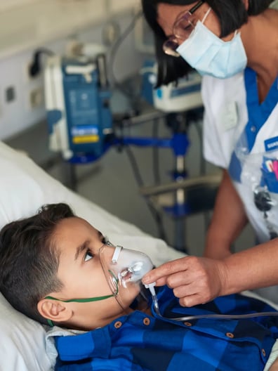 En sjuksköterska tar hand om ett barn i en sjukhussäng.