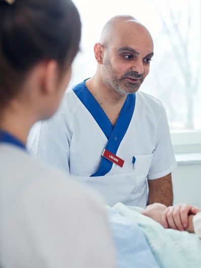 En sjuksköterska pratar med en patient i en sjukhussäng.