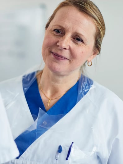 En kvinna i vit labbrock pratar med en annan kvinna.