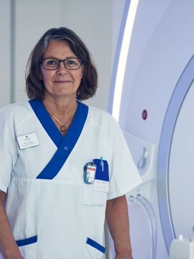 En kvinna i vit labbrock står bredvid en maskin.