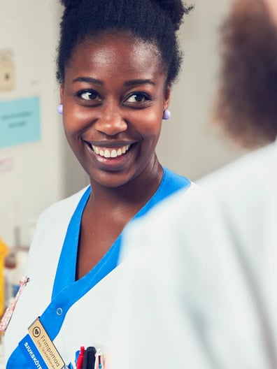 En leende kvinna i vit labbrock.