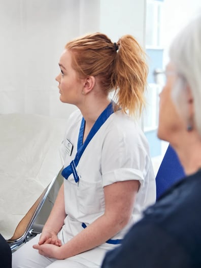 En sjuksköterska pratar med en patient på ett sjukhus.