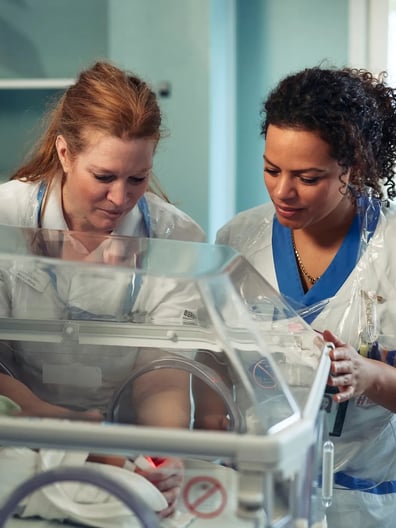 Två barnmorskor undersöker ett spädbarn.