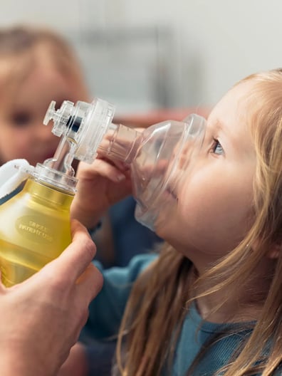 En liten flicka som får hjälp att andas lugnande gas.