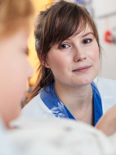 En läkare tittar mot kameran och ler.