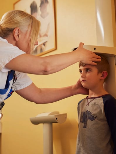 En sjuksköterska mäter en pojke.
