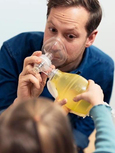 En pappa visar för sin lilla dotter att det är tryggt att andas medicinsk syrgas.