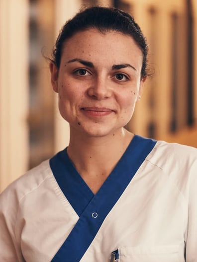 En kvinna i vårdkläder står i en korridor.