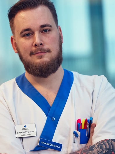 En sjuksköterska som korsar armarna och tittar mot kameran.