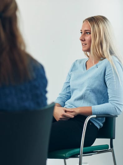 En kvinna sitter i en stol och pratar med en logoped.