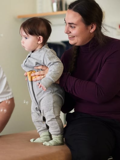 En mamma håller i sitt barn som tittar på såpbubblor.