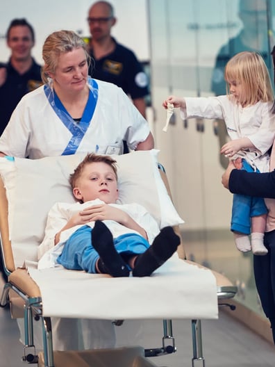 En kvinna skjutsar ett barn i en sjukhussäng.