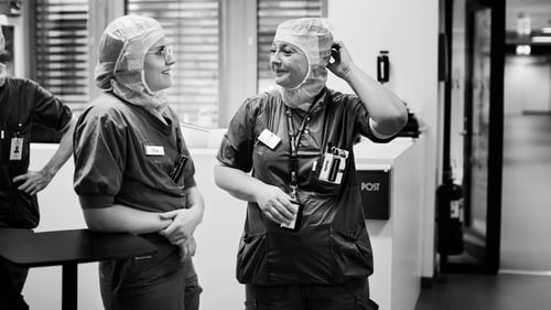 Två operationsklädda personer står i en sjukhuskorridor