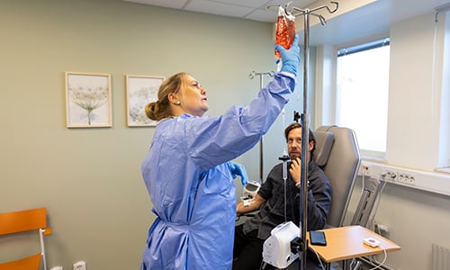 Patient sitter i en stol och får dropp