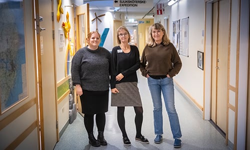 Tre personer står i en korridor