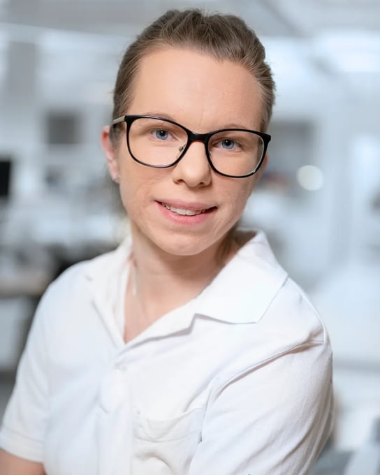 A woman wearing glasses and a white shirt.