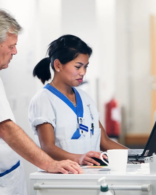 En man och en kvinna står framför en bärbar dator.