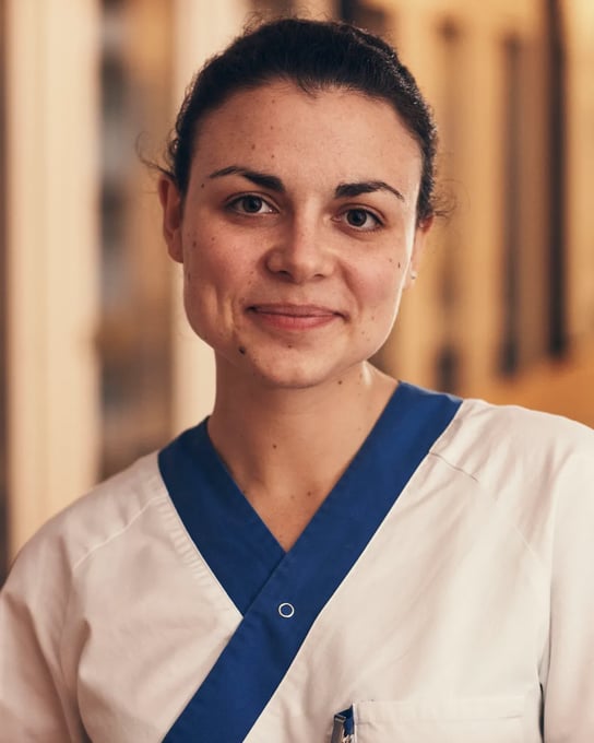 En kvinna i vårdkläder står i en korridor.