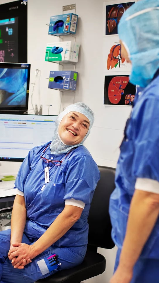 Två kvinnor i operationskläder pratar med varandra.