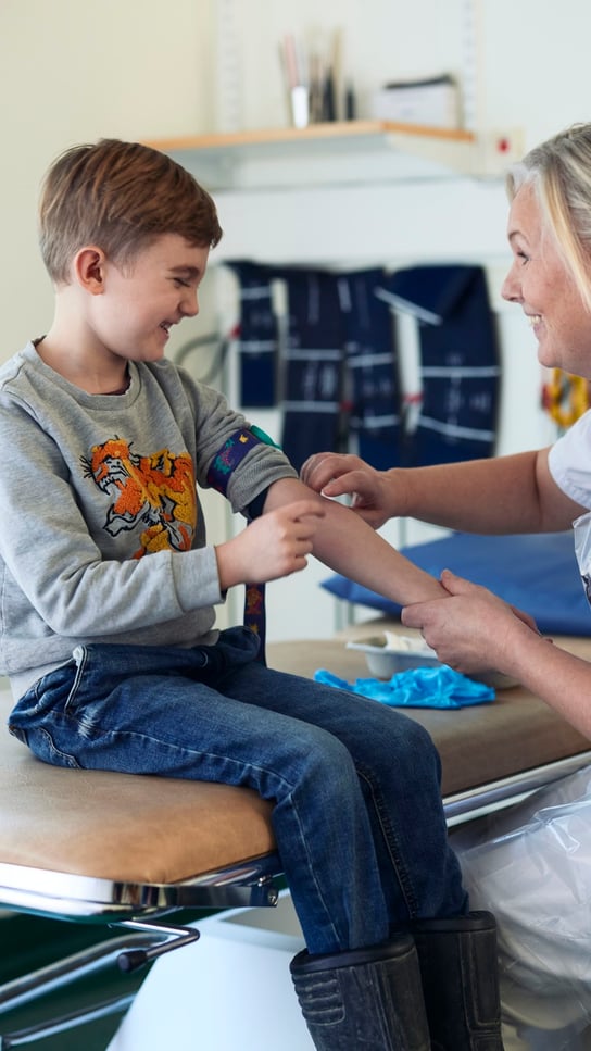 En kvinna sitter på en stol bredvid en liten pojke.