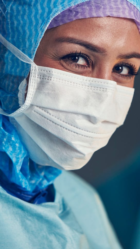 En kvinna iförd kirurgmask och operationskläder.