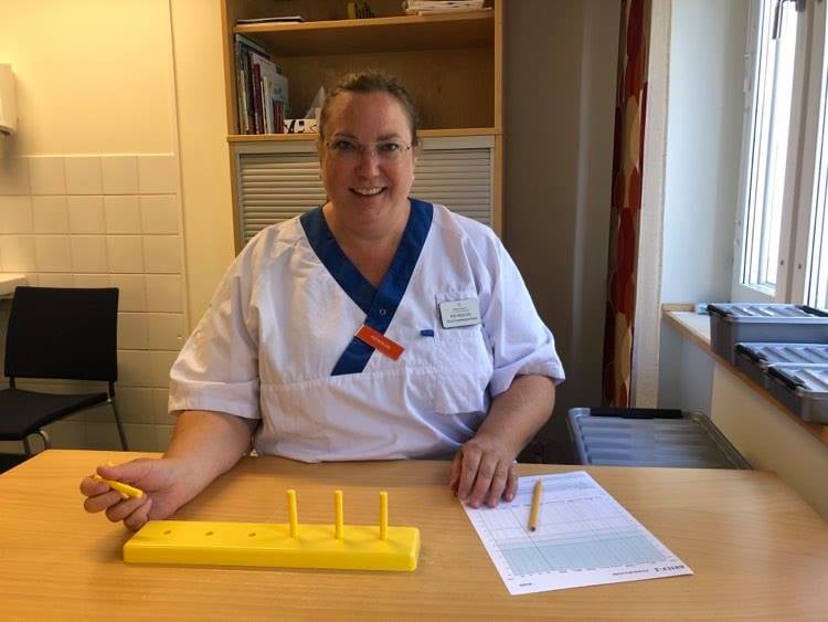 Kvinnlig psykolog i vita arbetskläder sitter vid bord.