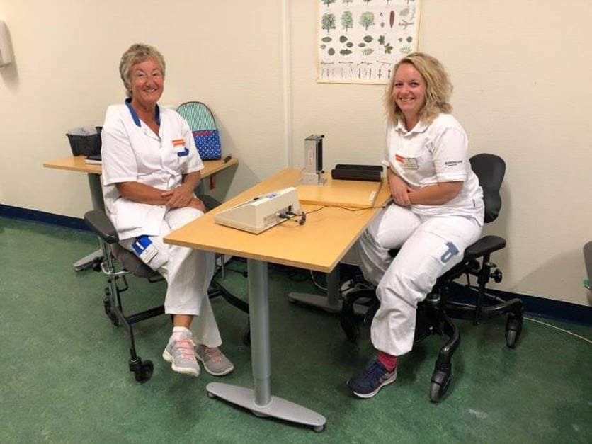 Två glada kvinnliga arbetsterapeuter i vita arbetskläder.