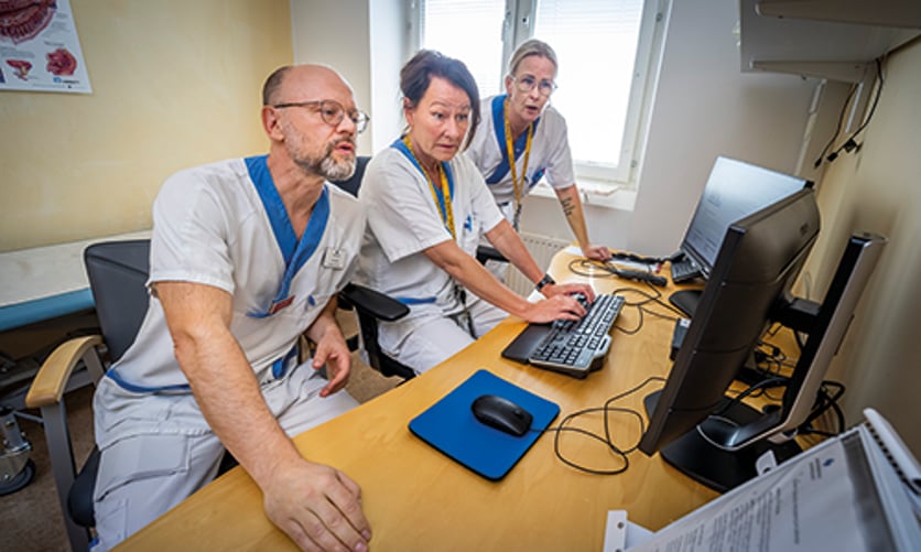 Tre personer sitter vid ett skrivbord