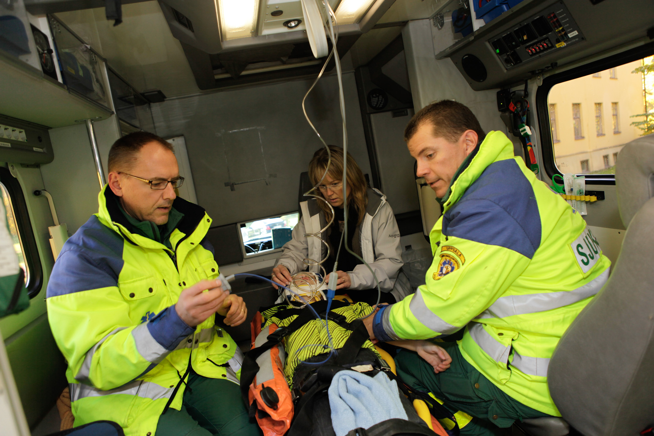 Pojken ligger i ambulansen och personalen sitter brevid.