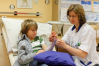 Sjuksköterskan sätter på en vit strumpa på armen på pojken.