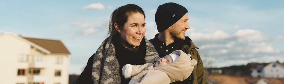 Man och kvinna utomhus i vinterkläder med nyfött barn