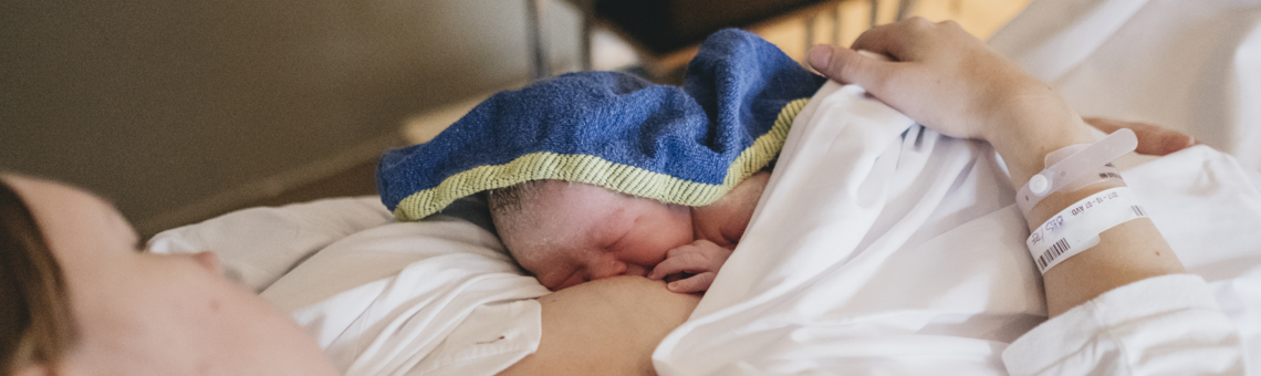Nyfödd bebis insvept i filt ammas