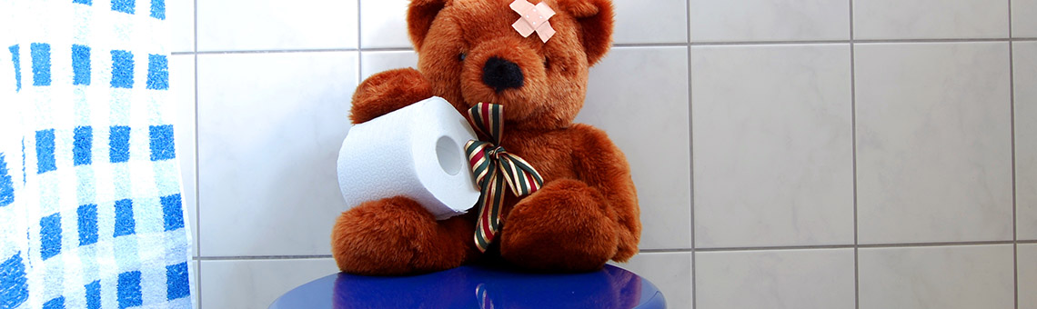 Nallebjörn sitter på toalett och håller i en toalettpappersrulle.