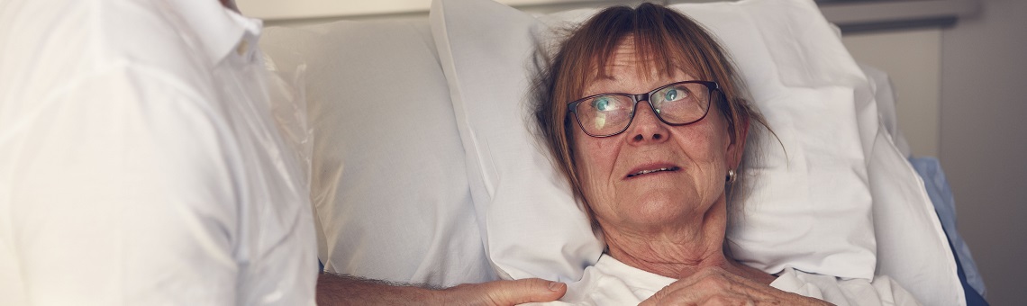 Kvinnlig patient i säng pratar med vårdpersonal.