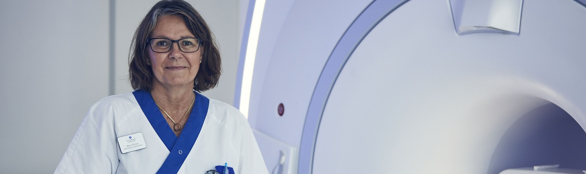 Kvinnlig röntgensjuksköterska står vid röntgenmaskin.