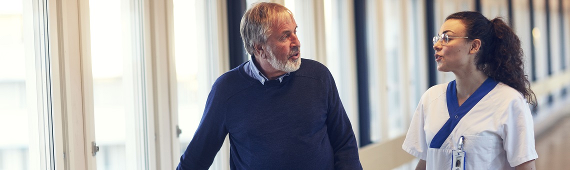 Patient och vårdpersonal samtalar i korridor.