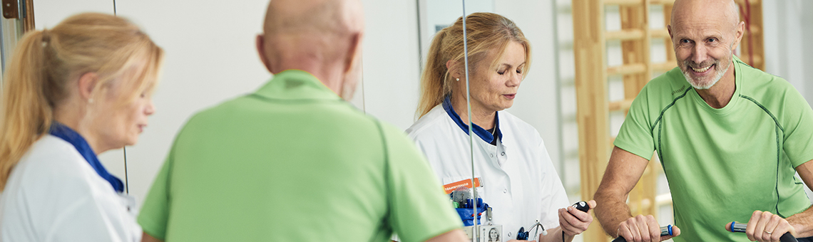 Fysioterapeut instruerar patient på träningscykel.